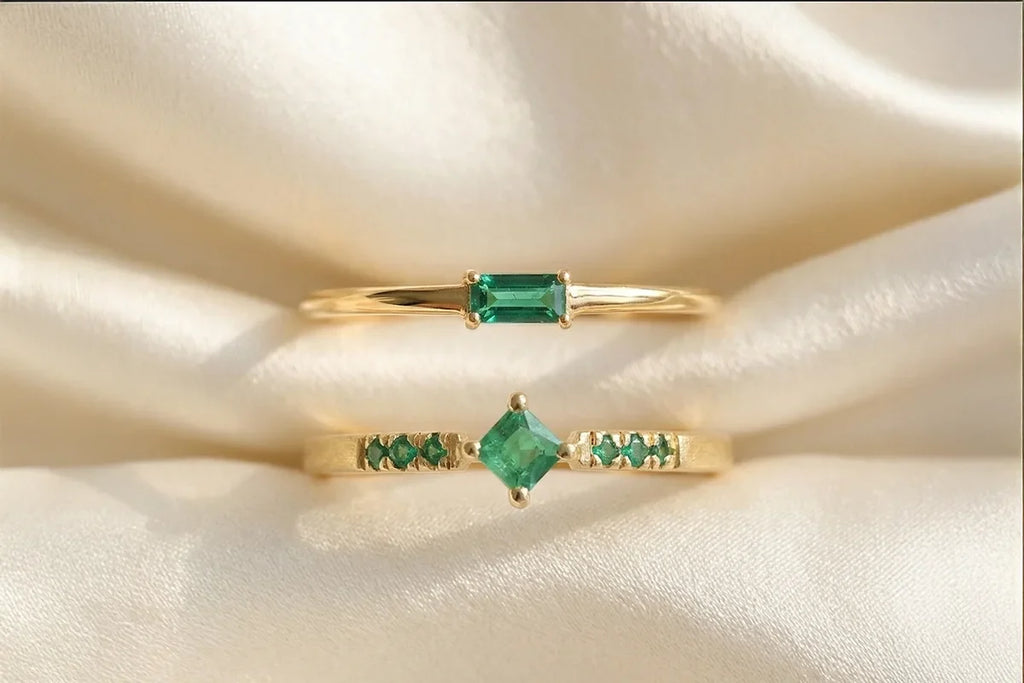 Mayuri emerald rings arranged on ivory satin