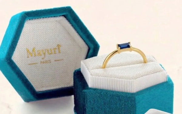Sapphire ring in yellow gold in its Mayuri velvet case, beside the polishing cloth
