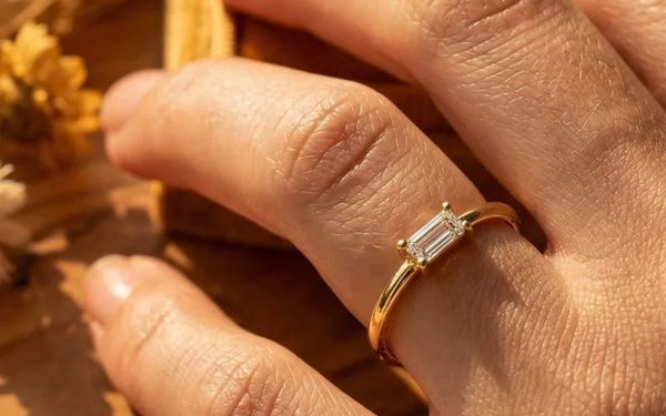 Emerald cut diamond solitaire ring in 18K yellow gold worn on the finger