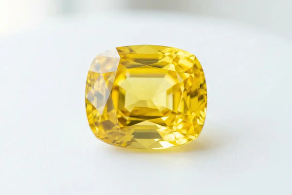 Cushion cut yellow sapphire, a brilliant precious stone with golden hues, symbol of wisdom in Vedic jewellery
