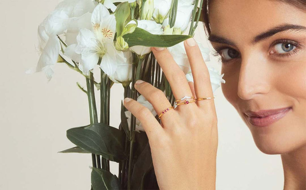 Fine vermeil stacking rings set with rubies and diamonds, worn with a bouquet of white flowers