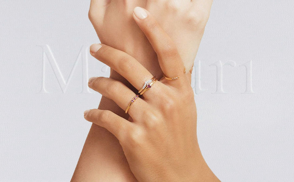 Fine 18K yellow gold rings set with diamonds and rubies, worn layered across the fingers