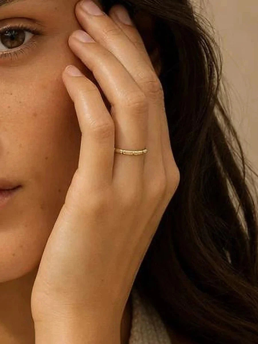 Bague Sobek 1,5 mm en or jaune portée, main contre le visage, recadrage sur l'anneau
