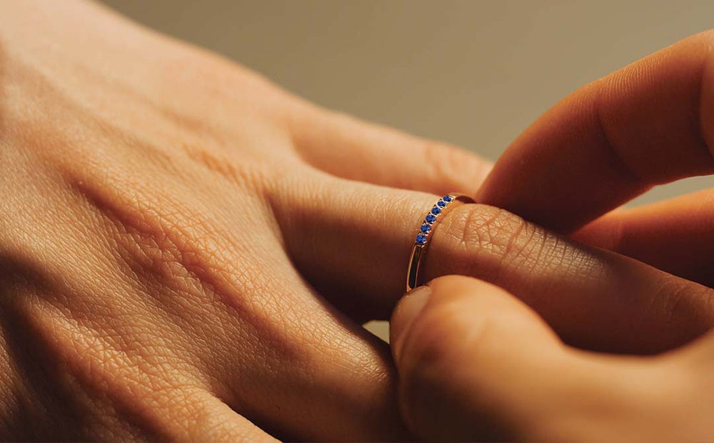 18K rose gold wedding ring set with blue sapphires, worn on a hand, jewellery care