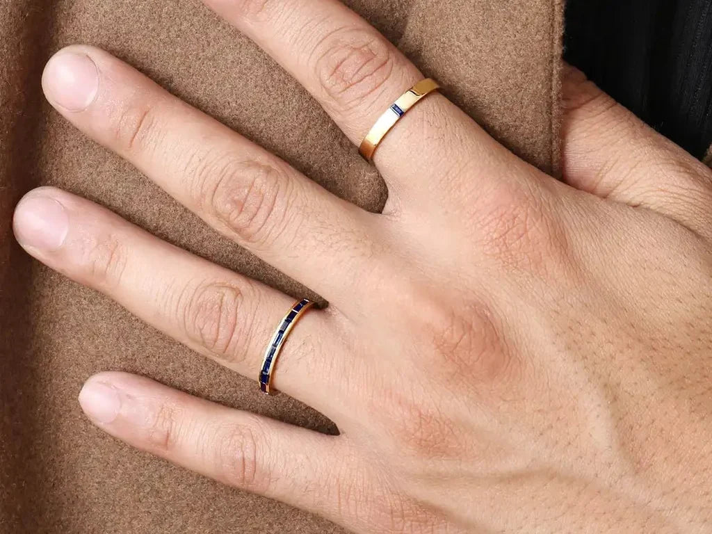 Two Mayuri men's engagement rings in 18K yellow gold set with sapphires, worn on the hand