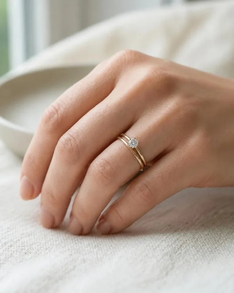 18K gold diamond solitaire and wedding ring duo, stacked on the left ring finger