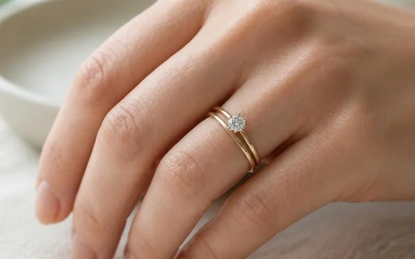 18K gold diamond solitaire and wedding ring duo, stacked on the left ring finger