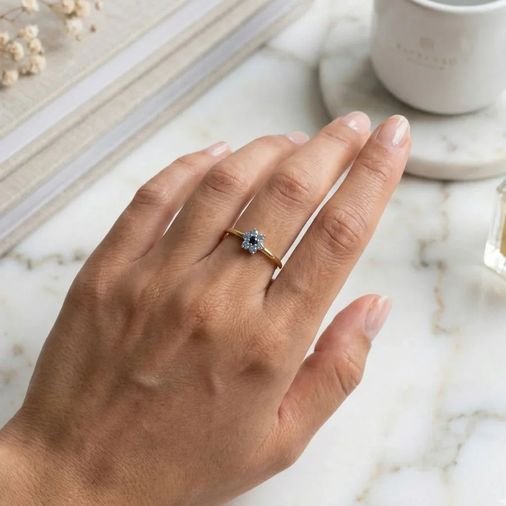Flower ring in 18K yellow gold, featuring a gradient of blue sapphires, worn on the ring finger, lifestyle setting