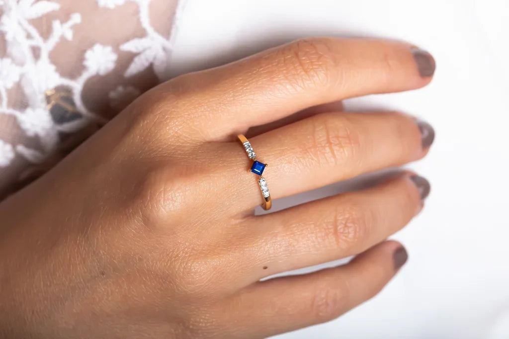 The Kali ring in 18K gold, set with a princess cut sapphire and diamonds, worn on the hand