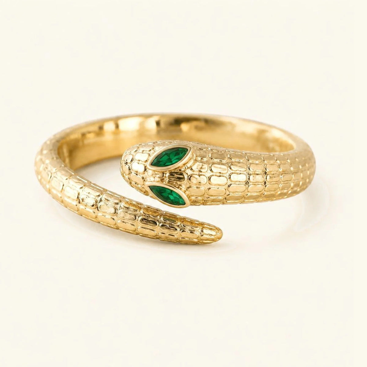 Méhen snake ring in 18K yellow gold, coiled scaled body and two marquise emeralds for the eyes