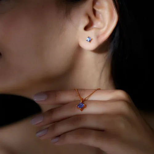 A tanzanite princess cut pendant necklace and earrings in 18K gold, worn