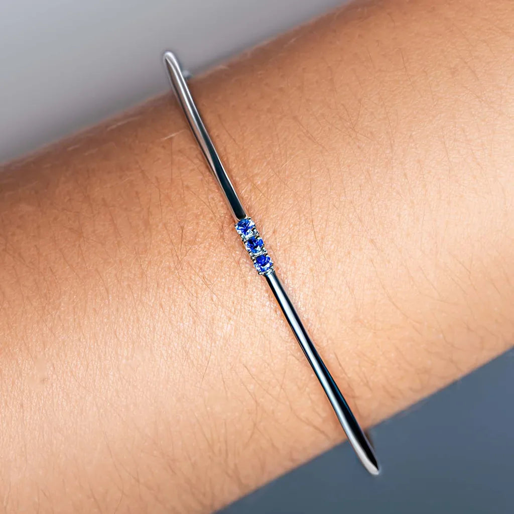 Tina fine bangle in 925 silver set with three blue sapphires, worn at the wrist