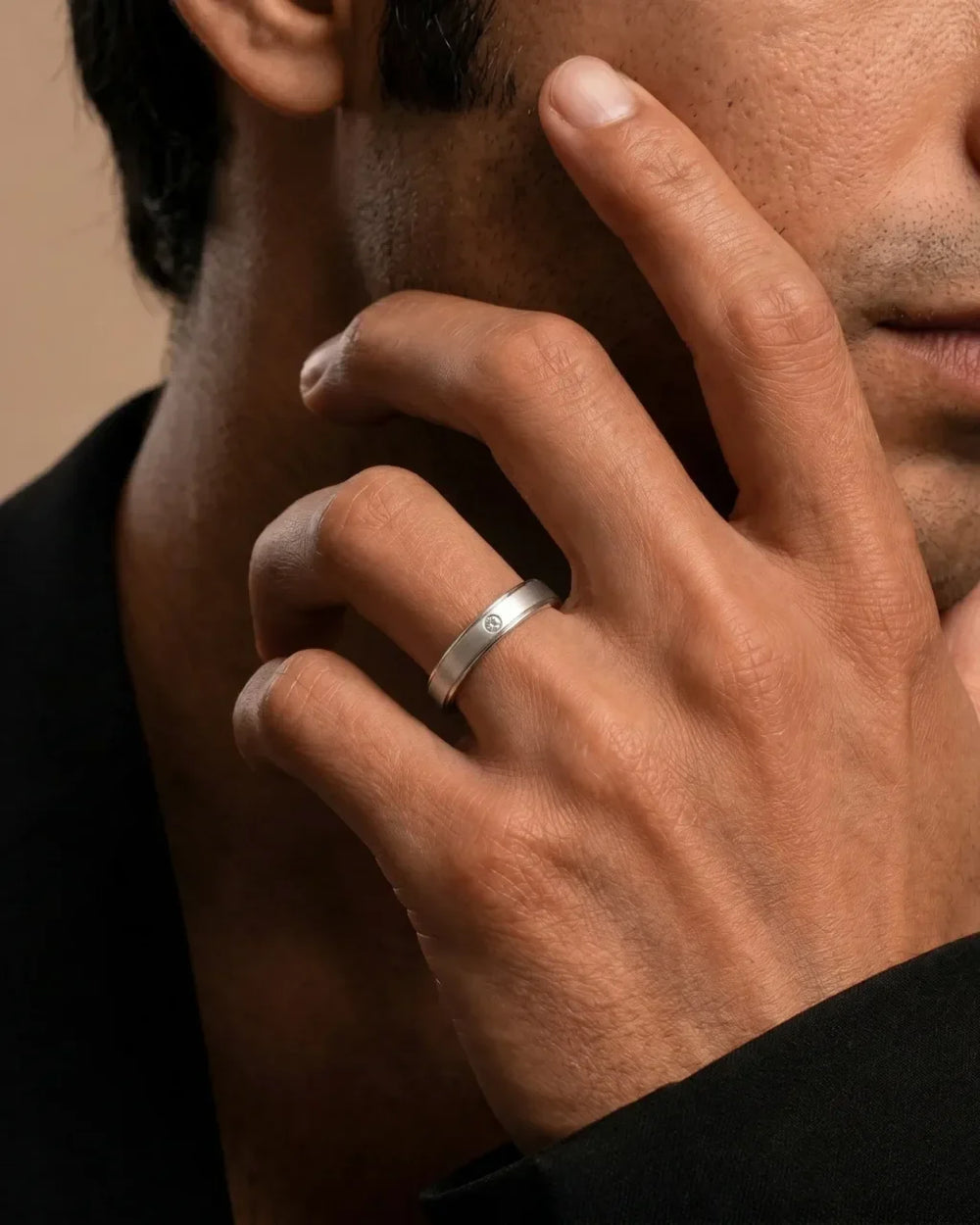 Platinum wedding ring set with diamonds worn on the finger on a cream background, Mayuri jewellery care