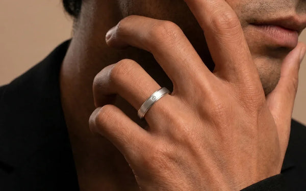 Platinum wedding ring set with diamonds worn on the finger on a cream background, Mayuri jewellery care