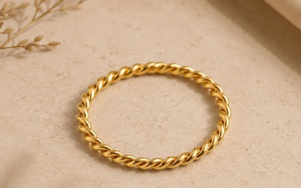 Twisted Musubi wedding ring in 18K yellow gold on a natural beige background, by Mayuri
