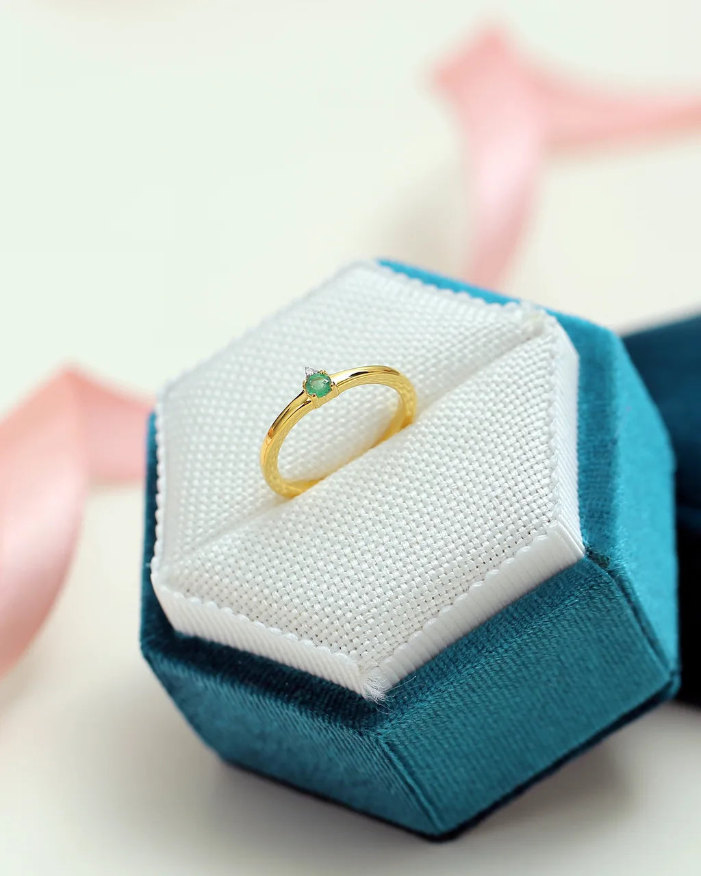 The Devi solitaire ring featuring an emerald and diamonds in 18K yellow gold by Mayuri, presented in its jewellery case