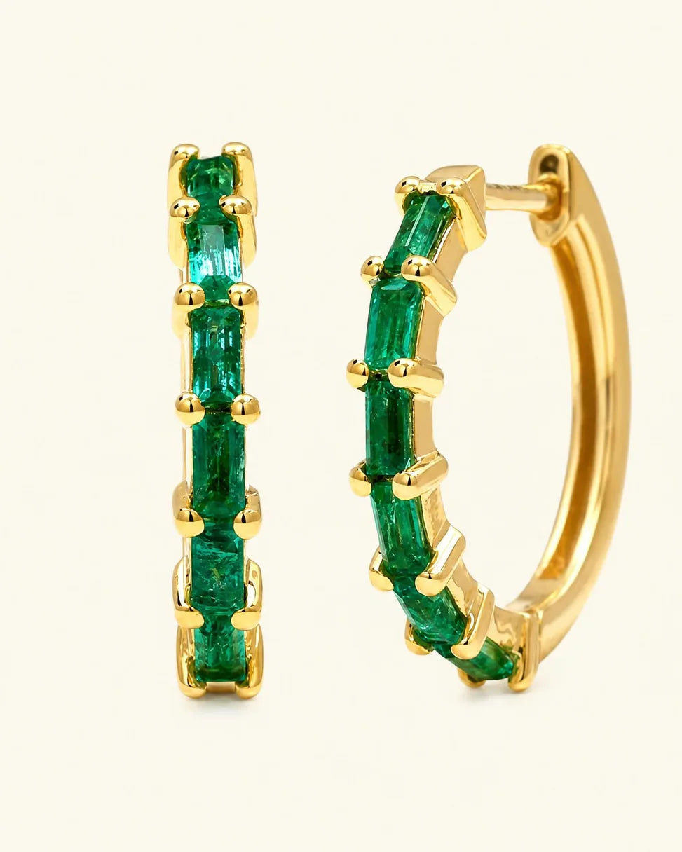 Yatra hoops in 18K yellow gold set with baguette emeralds in varying shades of green, by Mayuri