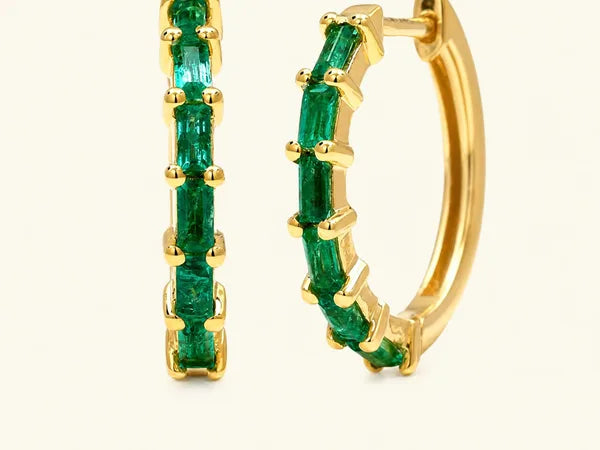 Yatra hoops in 18K yellow gold set with baguette emeralds in varying shades of green, by Mayuri