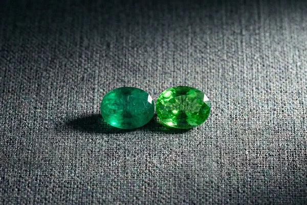 Oval-cut emerald and tsavorite side by side, a comparison of two green gemstones in fine jewellery