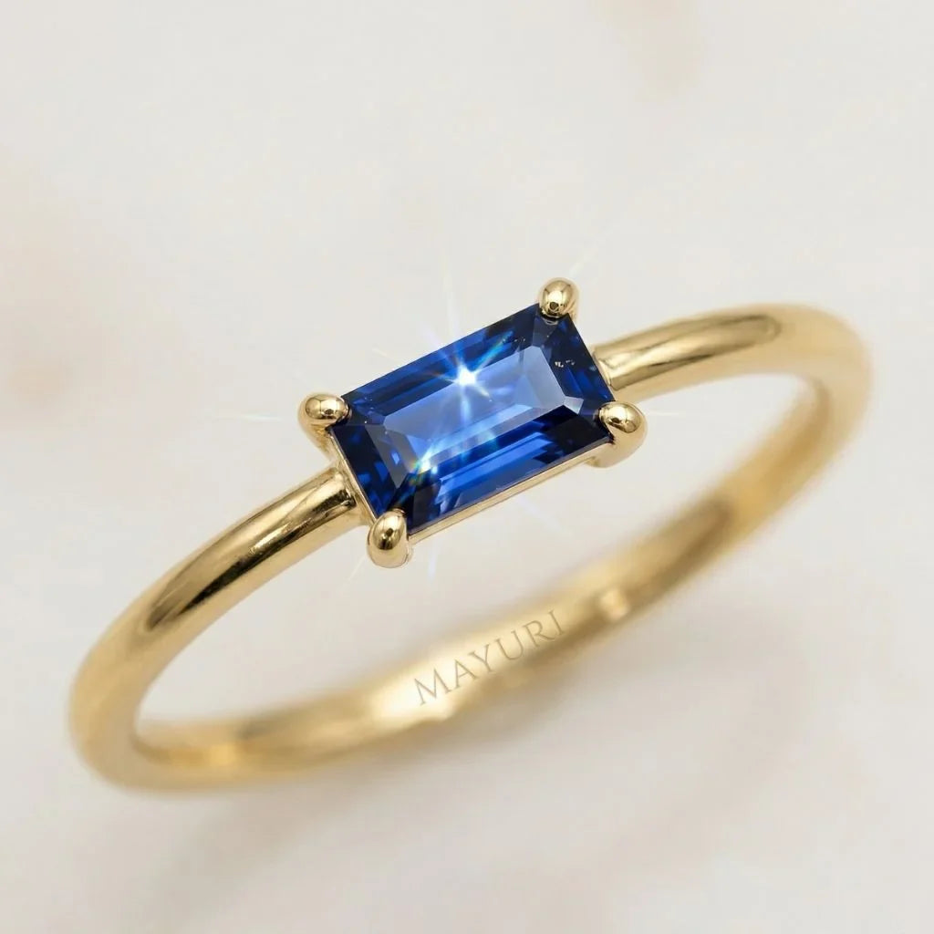 Close-up of a Mayuri 18K yellow gold ring set with a brilliant blue baguette sapphire