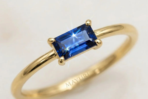 18K yellow gold ring set with a baguette-cut sapphire, shown with a soft brush and a glass of lukewarm water