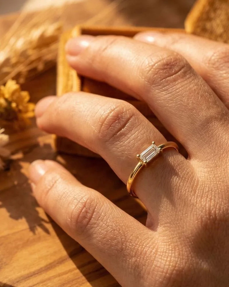 Emerald cut diamond solitaire ring in 18K yellow gold worn on the finger