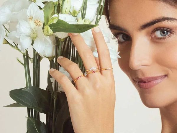 Fine vermeil stacking rings set with rubies and diamonds, worn with a bouquet of white flowers
