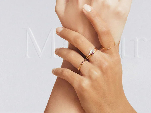 Fine 18K yellow gold rings set with diamonds and rubies, worn layered across the fingers