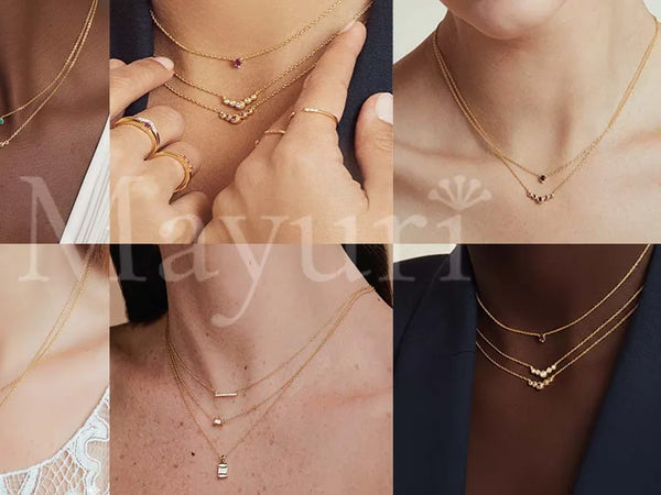 Delicate 18K gold necklaces adorned with coloured gemstones, sapphire, emerald and ruby, layered on fair and olive skin