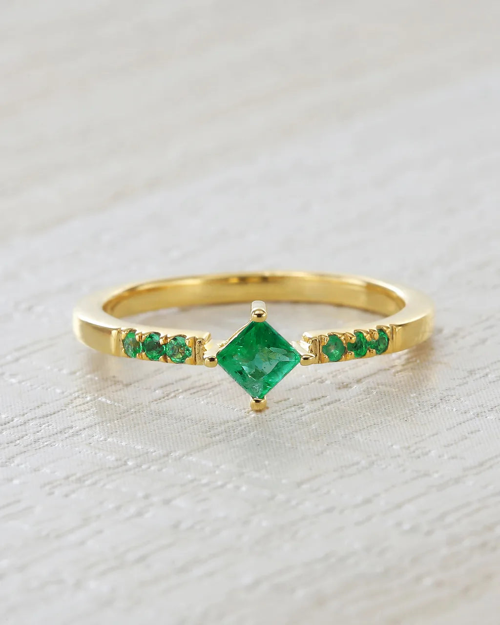 Kali ring in gold vermeil set with natural emeralds on a soft linen background