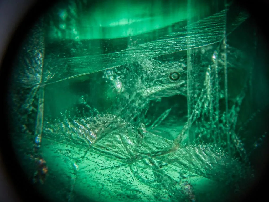 A loupe-magnified view of the characteristic garden inclusions within an untreated natural emerald