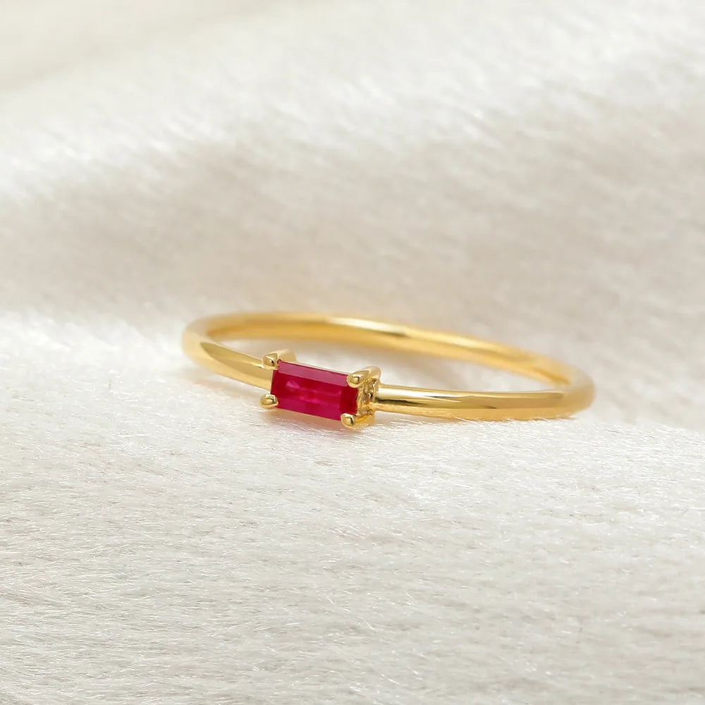Mayuri ring in 18K yellow gold set with an emerald cut ruby on a neutral background