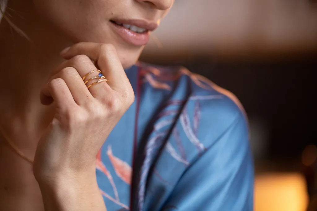 Blue sapphire and diamond rings in 18K yellow gold worn on the finger, from the Mayuri collection