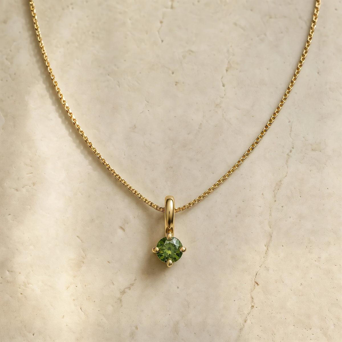 Collier Saral diamant vert en or jaune 18 carats, chaîne fine posée sur travertin