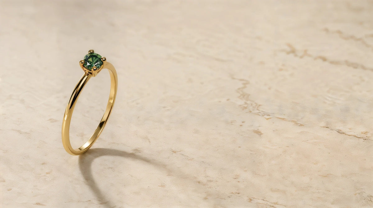Bague Saral diamant vert en or jaune 18 carats posée sur pierre de travertin, lumière douce